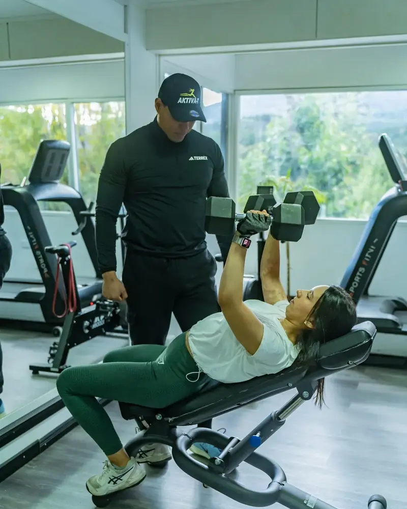 Entrenador guiando a una socia en una sesión personalizada