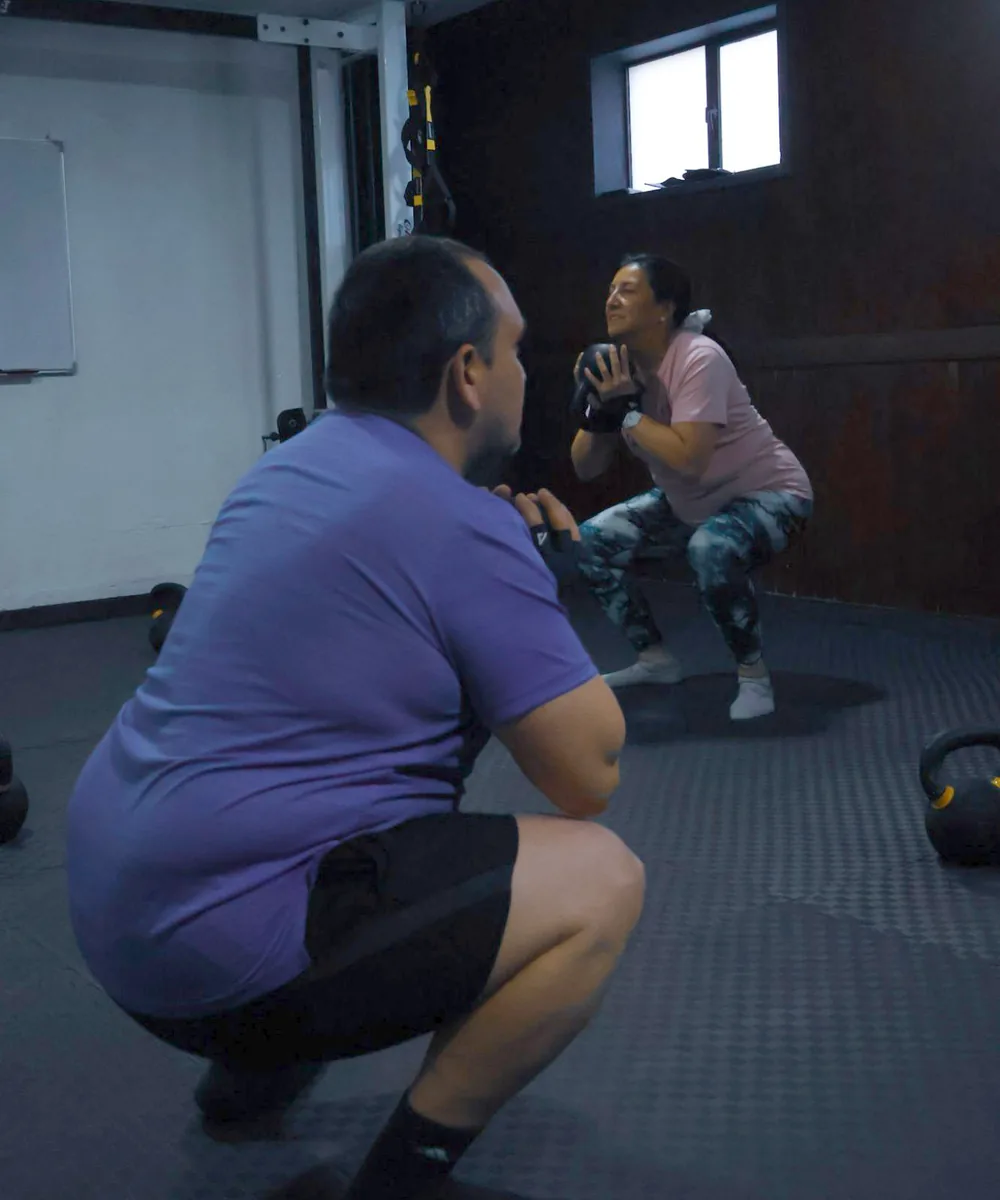 Dos alumnos haciendo sentadilla con kettlebell en una clase de Fundamentos del Studio Aktiva-T